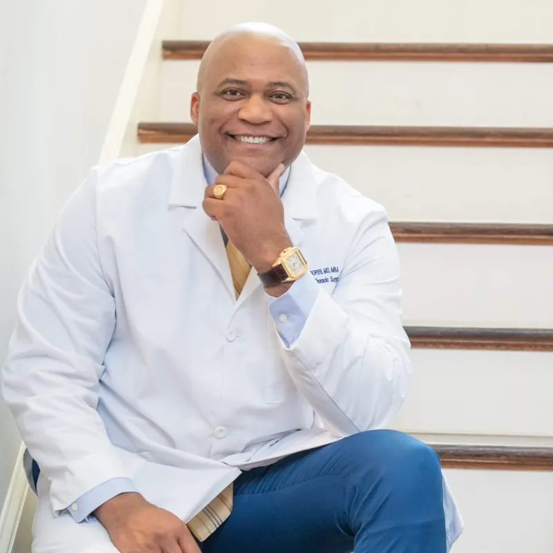 Dr. Cooper in a white coat seated on a staircase