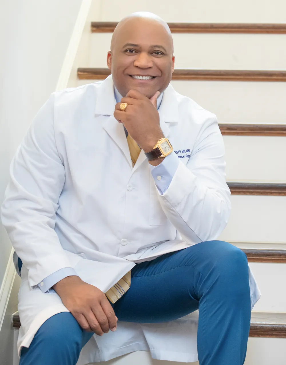 Dr. Cooper in a white coat, smiling, seated on a staircase
